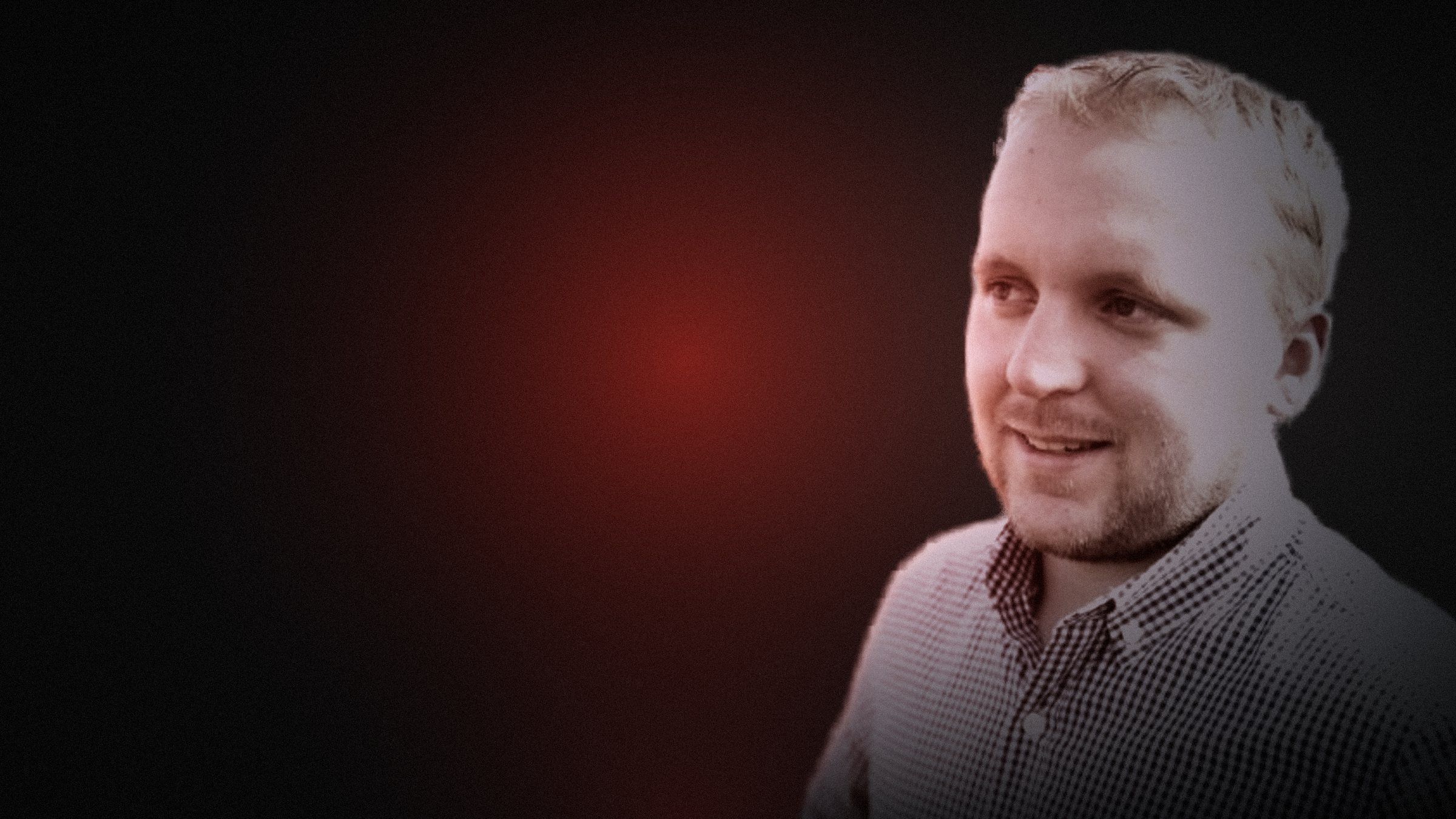 Kyle Pretsch in the dark, eyeing a glowing red button
